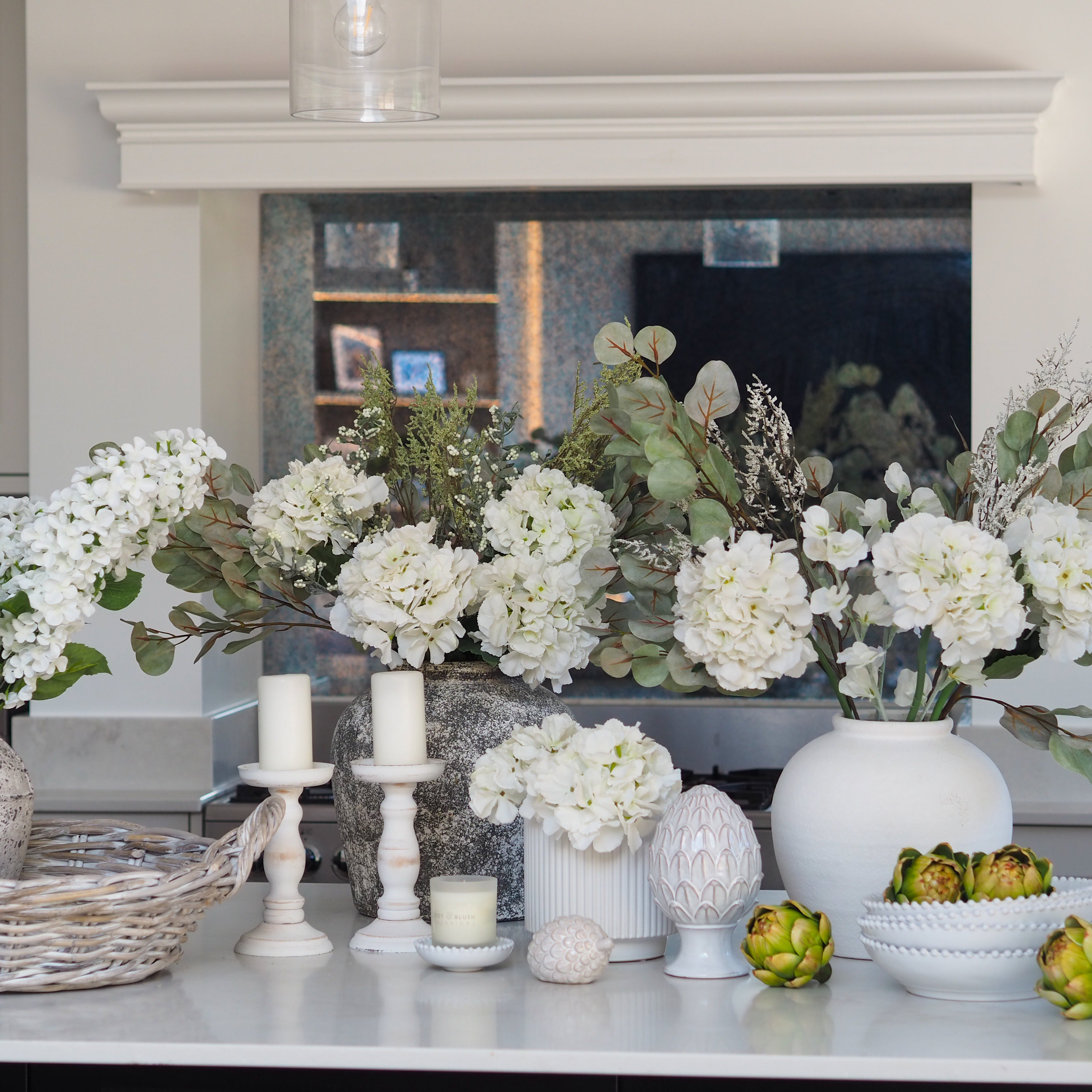 Decorative table setting with flowers, candles, and vases in a kitchen.