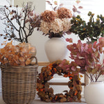 Autumn floral arrangement set featuring faux hydrangeas, eucalyptus, berries, and a leaf wreath in wicker and ceramic vases.