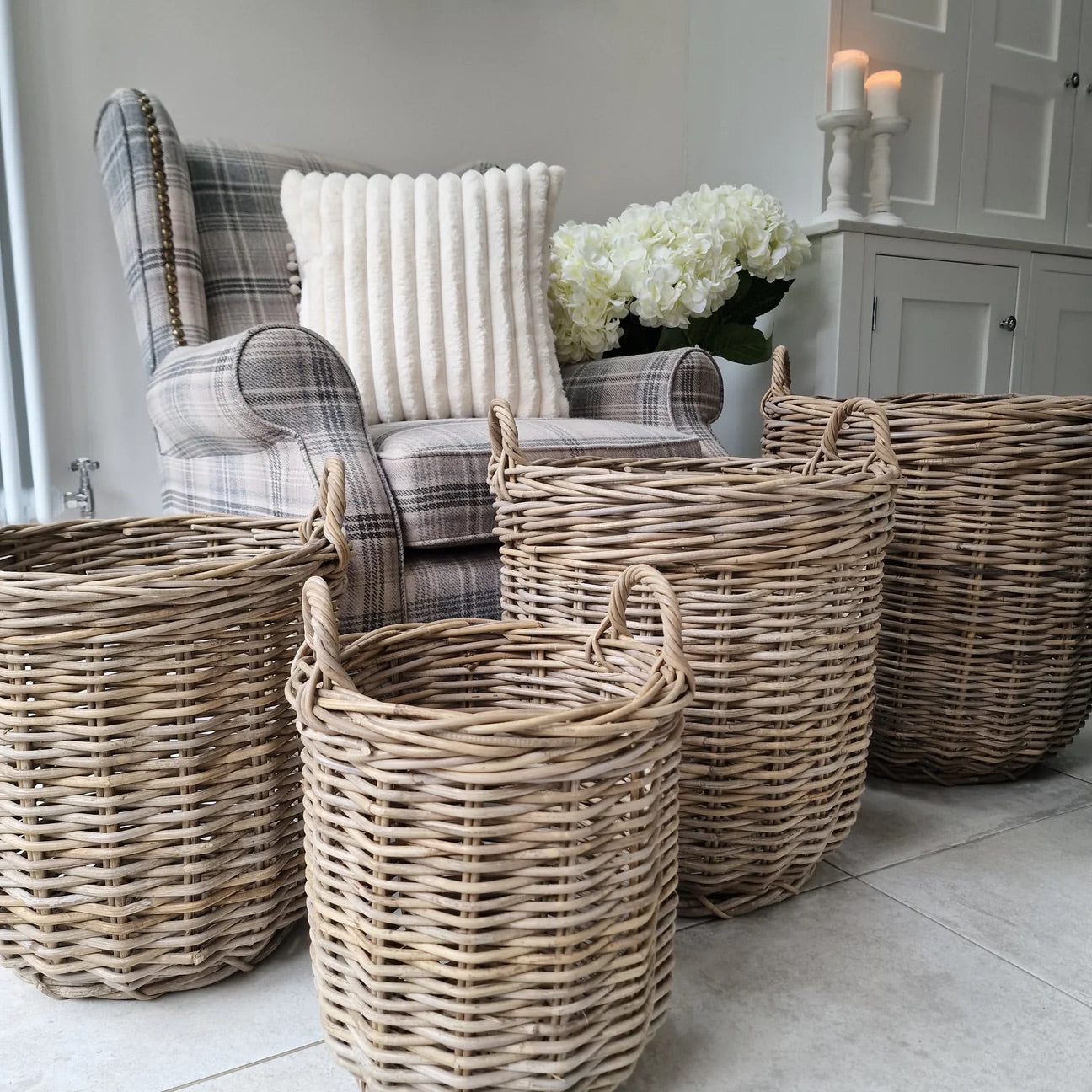A range of Rattan and Wicker Baskets in different sizes, in front of a grey tartan style chair